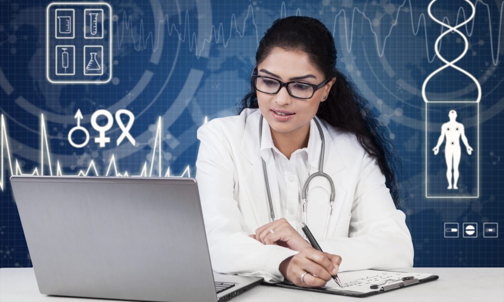 Indian doctor working with laptop and clipboard on desk, shot with modern futuristic background